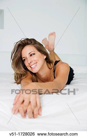 Stock Photograph - Portrait of a pretty blonde woman smiling in bed. Fotosearch