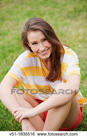 Portrait of a pretty young woman relaxing in park smiling at camera View Large Photo Image Stock Photograph - Portrait of a pretty young woman relaxing in park smiling at camera. Fotosearch