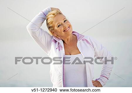 Stock Image - Portrait of a senior adult woman stretching her neck at the beach. Fotosearch