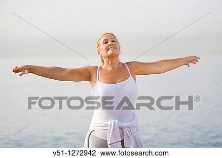 Stock Image - Portrait of a senior adult woman stretching at the beach. Fotosearch