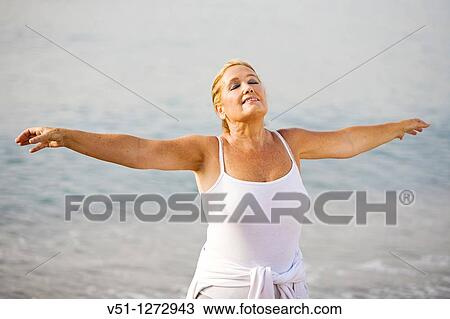 Stock Image - Portrait of a senior adult woman stretching at the beach. Fotosearch
