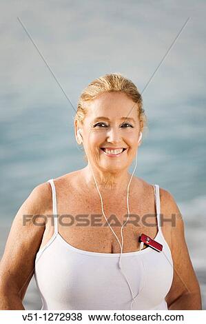 Portrait of a senior adult woman listening to music while she makes sport at the beach View Large Photo Image Stock Photo - Portrait of a senior adult woman listening to music while she makes sport at the beach. Fotosearch
