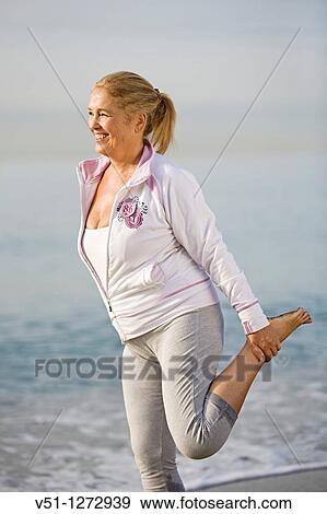 Stock Photo - Portrait of a senior adult woman stretching her legs at the beach. Fotosearch
