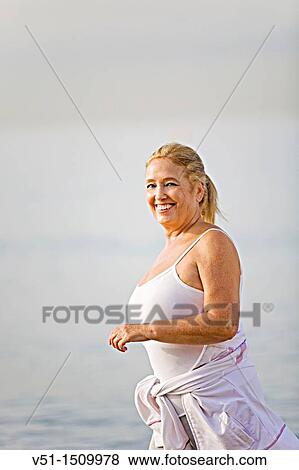 Stock Photo - Portrait of a senior adult woman running at the beach. Fotosearch