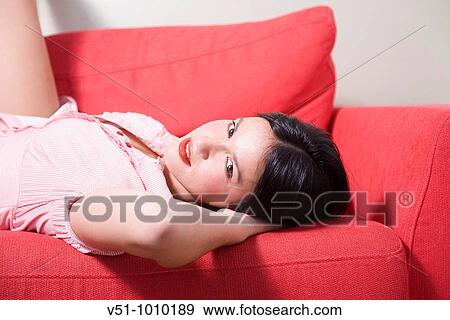 Stock Photo - Portrait of a sensual brunette woman on the couch. Fotosearch