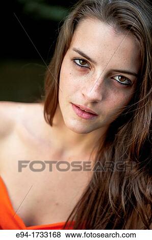 Stock Photo - Portrait of a serious 20 year old brunette woman looking directly at the camera.. Fotosearch