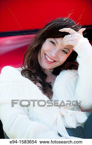 Portrait of a smiling 25 year old brunette woman wearing a white sweater outdoors View Large Photo Image Picture - Portrait of a smiling 25 year old brunette woman wearing a white sweater outdoors. Fotosearch