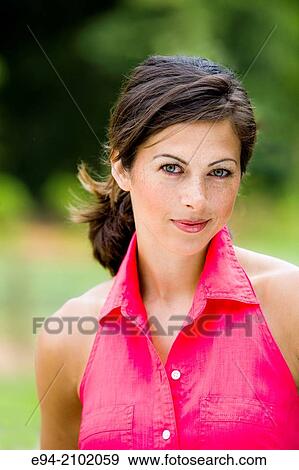 Stock Photo - Portrait of a smiling 27 year old brunette woman looking at the camera, outdoors.. Fotosearch