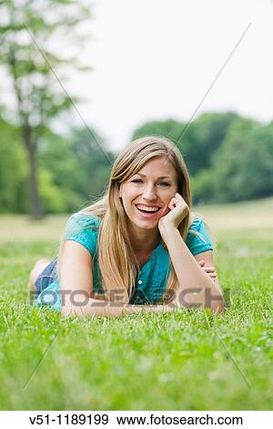 Portrait of a smiling blonde woman laying in the park View Large Photo Image Stock Photo - Portrait of a smiling blonde woman laying in the park. Fotosearch