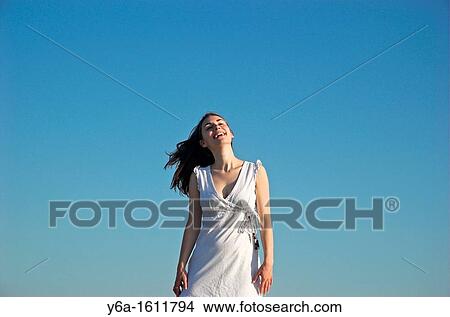 Portrait of a smiling young woman wearing summer dress against blue sky View Large Photo Image Picture - Portrait of a smiling young woman wearing summer dress against blue sky. Fotosearch