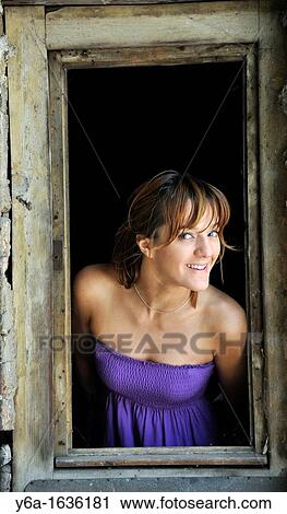 Portrait of a smiling young woman standing in window frame View Large Photo Image Stock Image - Portrait of a smiling young woman standing in window frame. Fotosearch