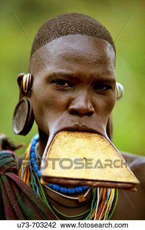 Stock Image - Portrait of a Surma woman wearing a wooden disc plate in her lower lip, Ethiopia. Fotosearch