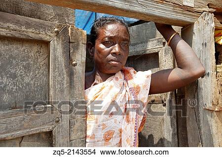 Picture - Portrait of a tribal woman standing at the entrance door of her house. Murmu tribe. Jamuniatand village, Bokaro district, Jharkhand.. Fotosearch