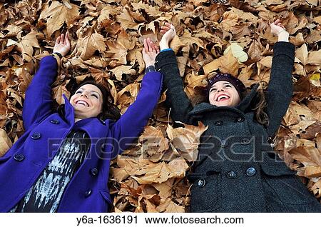Portrait of a two young woman lying on autumn leaves from a bird's eye view laughing and having fun View Large Photo Image Stock Image - Portrait of a two young woman lying on autumn leaves from a bird's eye view laughing and having fun. Fotosearch