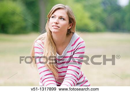 Portrait of a woman in the park sitting in a bench and daydreaming View Large Photo Image Stock Photo - Portrait of a woman in the park sitting in a bench and daydreaming. Fotosearch