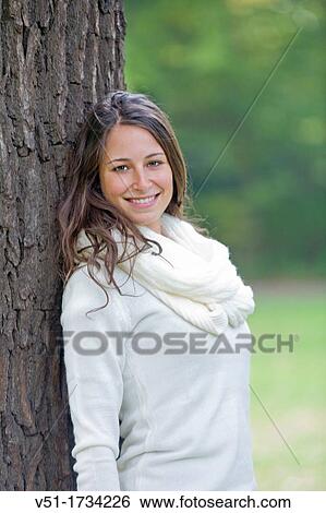 Portrait of a woman leaning in a tree in the park in Autumn, smiling at camera View Large Photo Image Stock Photograph - Portrait of a woman leaning in a tree in the park in Autumn, smiling at camera. Fotosearch