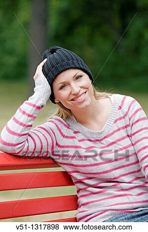 Portrait of a woman sitting in a bench in the park in Autumn smiling at camera View Large Photo Image Stock Photo - Portrait of a woman sitting in a bench in the park in Autumn smiling at camera. Fotosearch