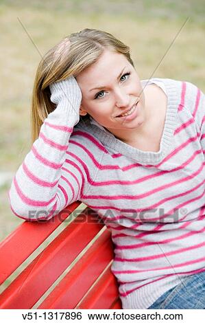 Portrait of a woman sitting in a bench in the park in Autumn smiling at camera View Large Photo Image Stock Photograph - Portrait of a woman sitting in a bench in the park in Autumn smiling at camera. Fotosearch