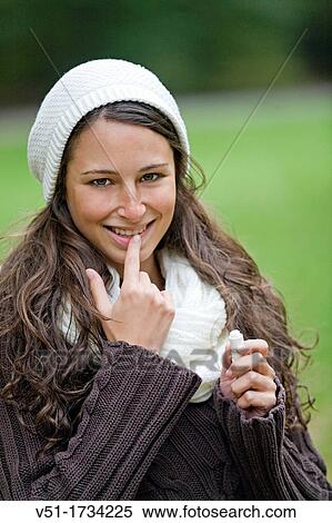 Stock Photography - Portrait of a woman with a lipsalve in the park looking at camera. Fotosearch