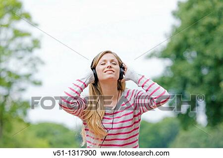 Portrait of a woman with closed eyes listening to music in the park View Large Photo Image Stock Image - Portrait of a woman with closed eyes listening to music in the park. Fotosearch
