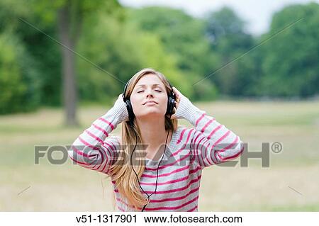 Portrait of a woman with closed eyes listening to music in the park View Large Photo Image Stock Image - Portrait of a woman with closed eyes listening to music in the park. Fotosearch
