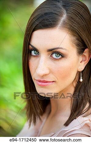 Stock Image - Portrait of a young a 22 year old brunette woman wearing a dress in a garden setting. Fotosearch