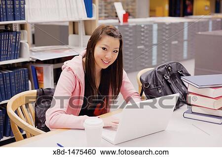 Portrait of a young Asian woman studying with her laptop computer in a library. View Large Photo Image Stock Image - Portrait of a young Asian woman studying with her laptop computer in a library.. Fotosearch