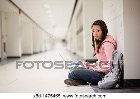 Portrait of a young Asian woman using her laptop computer while sitting on floor in school hallway. View Large Photo Image Stock Photography - Portrait of a young Asian woman using her laptop computer while sitting on floor in school hallway.. Fotosearch