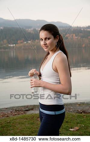 Portrait of a young athletic woman holding a bottle of water, Inlet Park, Port Moody, British Columbia, Canada View Large Photo Image Stock Image - Portrait of a young athletic woman holding a bottle of water, Inlet Park, Port Moody, British Columbia, Canada. Fotosearch