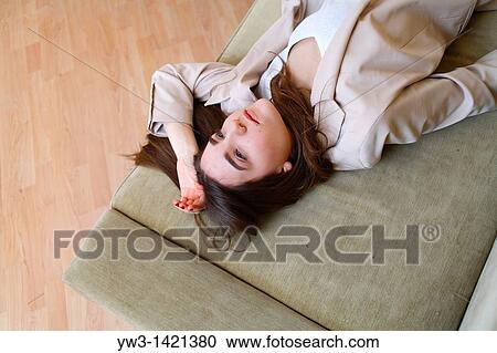 Stock Image - Portrait of a young blond woman lying on sofa. Fotosearch