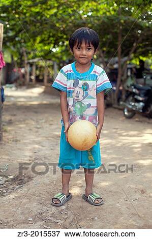 Stock Photo - Portrait of a young boy with a ball in a small village outside of Phnom Penh, Cambodia.. Fotosearch