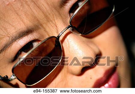 Portrait of a young Chinese woman, eyes looking over sun glasses at camera View Large Photo Image Stock Photo - Portrait of a young Chinese woman, eyes looking over sun glasses at camera. Fotosearch
