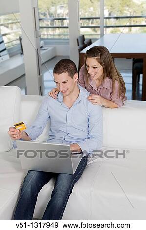 Portrait of a young couple buying with credit card in internet on the sofa View Large Photo Image Stock Photo - Portrait of a young couple buying with credit card in internet on the sofa. Fotosearch