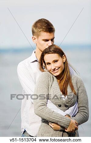 Portrait of a young couple holding and kissing by the sea View Large Photo Image Picture - Portrait of a young couple holding and kissing by the sea. Fotosearch