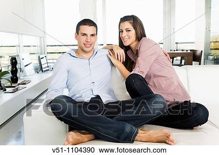 Stock Image - Portrait of a young couple on the sofa. Fotosearch