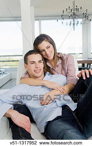 Stock Image - Portrait of a young couple on the sofa. Fotosearch
