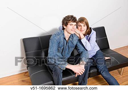 Stock Image - Portrait of a young couple on the sofa. Fotosearch