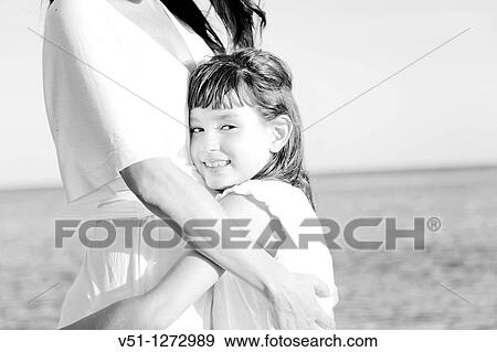 Portrait of a young girl embracing her mother and looking at camera View Large Photo Image Stock Photo - Portrait of a young girl embracing her mother and looking at camera. Fotosearch