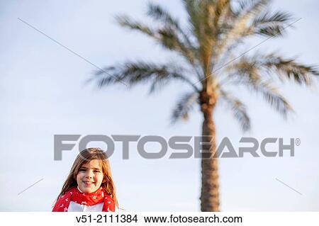 Picture - Portrait of a young girl smiling at camera by the sea. Fotosearch