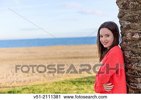 Portrait of a young girl smiling at camera at the beach View Large Photo Image Stock Image - Portrait of a young girl smiling at camera at the beach. Fotosearch