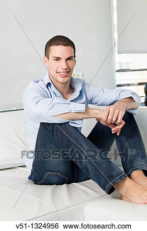 Portrait of a young man relaxing in sofa View Large Photo Image Stock Photograph - Portrait of a young man relaxing in sofa. Fotosearch