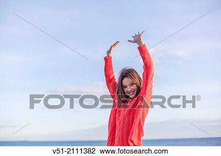 Stock Image - Portrait of a young playful girl smiling at the beach. Fotosearch