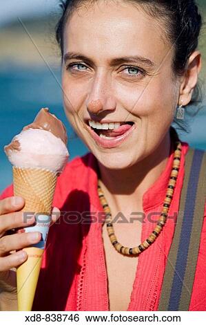 Portrait of a young woman eating a ice cream View Large Photo Image Stock Photograph - Portrait of a young woman eating a ice cream. Fotosearch