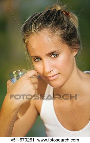 Portrait of a young woman holding a glass of water View Large Photo Image Stock Image - Portrait of a young woman holding a glass of water. Fotosearch