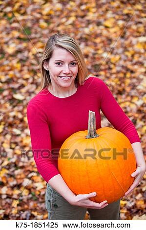 Portrait of a young woman holding a pumpkin View Large Photo Image Stock Photography - Portrait of a young woman holding a pumpkin. Fotosearch