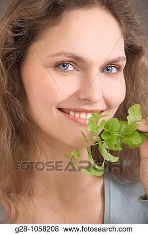 portrait of a young woman holding and smelling a sprig of mint View Large Photo Image Stock Photo - portrait of a young woman holding and smelling a sprig of mint. Fotosearch