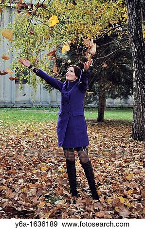 Portrait of a young woman outdoors throwing autumn leaves in air View Large Photo Image Stock Photo - Portrait of a young woman outdoors throwing autumn leaves in air. Fotosearch