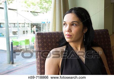 Portrait of a young woman sitting in a cafe and looking out of the window View Large Photo Image Stock Photograph - Portrait of a young woman sitting in a cafe and looking out of the window. Fotosearch