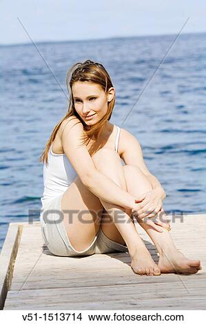 Portrait of a young woman smiling and sitting on a pier View Large Photo Image Picture - Portrait of a young woman smiling and sitting on a pier. Fotosearch