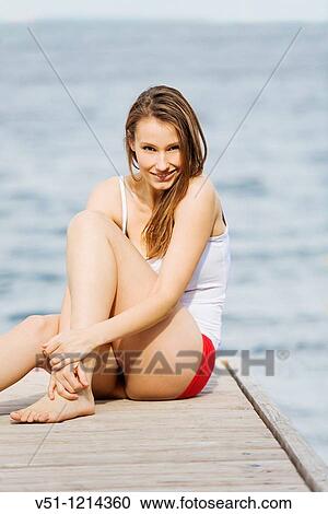 Portrait of a young woman smiling and sitting in a pier View Large Photo Image Stock Image - Portrait of a young woman smiling and sitting in a pier. Fotosearch